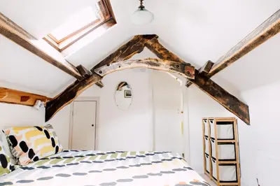 a bedroom with a bed and a ceiling with beams at The Barn at Ty Beic in Bala