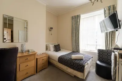 a bedroom with a bed and a chair and a mirror at Gwesty'r Marine Hotel & Spa in Aberystwyth
