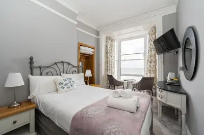a bedroom with a bed and a desk and a window at Gwesty'r Marine Hotel & Spa in Aberystwyth