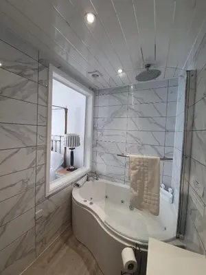 a bathroom with a tub and a glass shower at Gwesty'r Marine Hotel & Spa in Aberystwyth