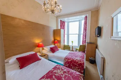 a bedroom with two beds and a chandelier at Gwesty'r Marine Hotel & Spa in Aberystwyth