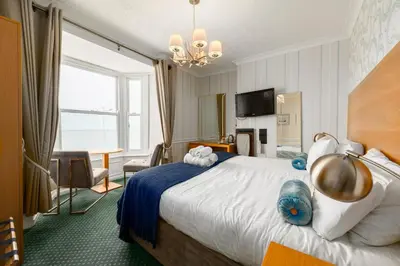a hotel room with a large bed and a table at Gwesty'r Marine Hotel & Spa in Aberystwyth