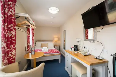 a small room with a bed and a desk at Gwesty'r Marine Hotel & Spa in Aberystwyth