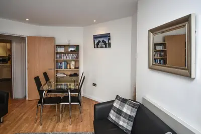 a living room with a glass table and chairs at Parc y Bryn Serviced Apartments in Aberystwyth