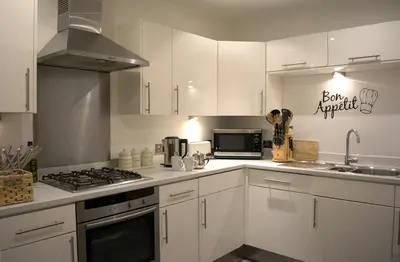 a kitchen with white cabinets and a stove top oven at Parc y Bryn Serviced Apartments in Aberystwyth