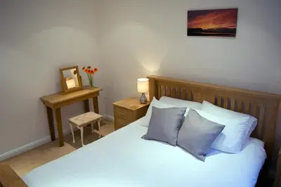 a bedroom with a bed with two pillows and a table at Parc y Bryn Serviced Apartments in Aberystwyth