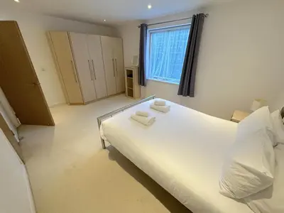 a bedroom with a large white bed and a window at Parc y Bryn Serviced Apartments in Aberystwyth