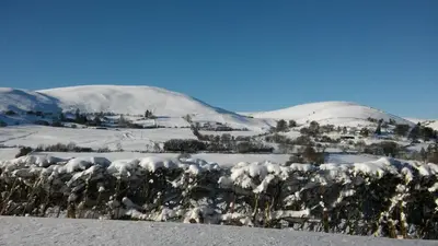 a mountain covered in snow with a town and trees at The Old School House in Llanbrynmair