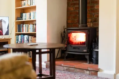 a wood stove in a living room with a table at Oak House in Mid Wales with Log Burner By Seren Short Stays in Machynlleth