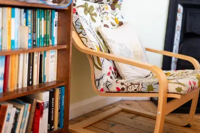a chair sitting next to a book shelf at Oak House in Mid Wales with Log Burner By Seren Short Stays in Machynlleth