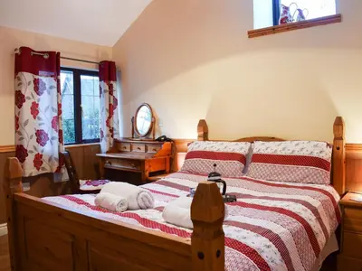 a bedroom with a bed with a red and white blanket at Ty Bach Twt in Llangeitho