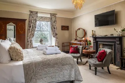 a bedroom with a bed and a fireplace and a television at Afon Rhaiadr Country House in Dolgellau