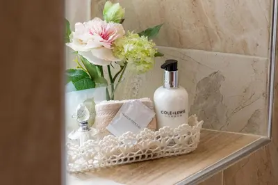 a bathroom shelf with a bottle of soap and flowers at Afon Rhaiadr Country House in Dolgellau