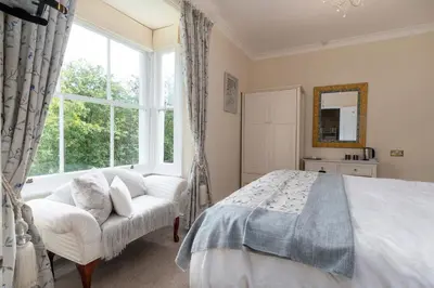 a bedroom with a bed and a large window at Afon Rhaiadr Country House in Dolgellau