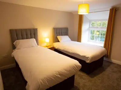 two beds in a hotel room with a window at Hafan in Llangollen