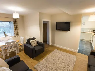 a living room with a couch and a tv on a wall at Hafan in Llangollen