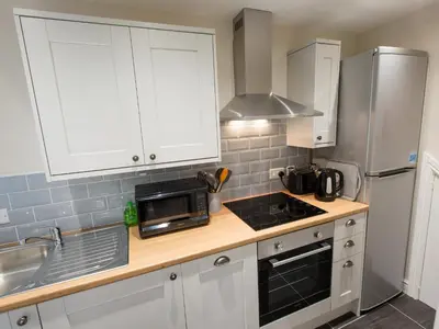a kitchen with white cabinets and a sink and a microwave at Catref in Llangollen