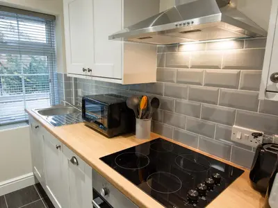 a kitchen with white cabinets and a black stove top oven at Catref in Llangollen