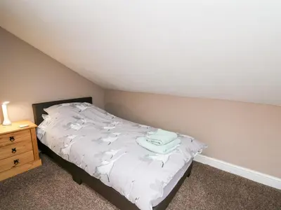 a bedroom with a bed with white sheets and a night stand at Fisher Granary in Lampeter
