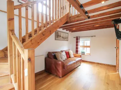 a living room with a couch and a staircase at Old Hall Barn 4 in Church Stretton