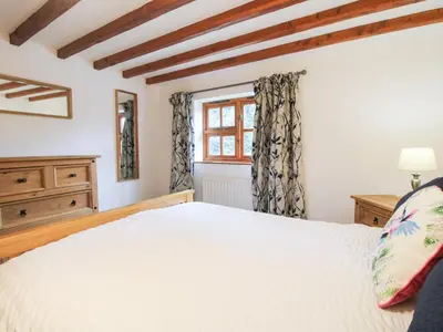 a bedroom with a white bed and a window at Old Hall Barn 4 in Church Stretton