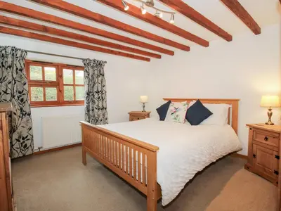 a bedroom with a wooden bed and a window at Old Hall Barn 4 in Church Stretton