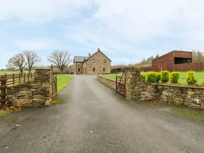 an old stone house on a road with a fence at Ty Berllan in Caersws