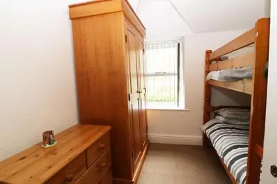a bedroom with a bunk bed and a wooden dresser at Heulwen in Barmouth