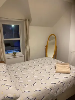 a bedroom with a bed and a mirror and a window at Heulwen in Barmouth