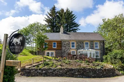 a stone house with a sign in front of it at Maes y Gwaelod in Llanwrtyd Wells