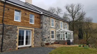 a brick house with a greenhouse on the side of it at Maes y Gwaelod in Llanwrtyd Wells
