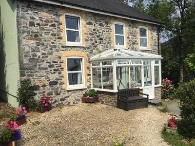 a house with a greenhouse on the side of it at Maes y Gwaelod in Llanwrtyd Wells