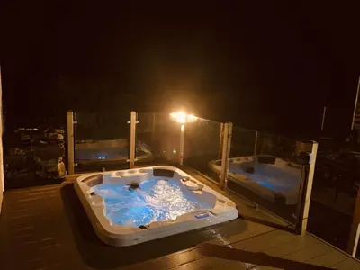 two hot tubs on a deck at night at Finest Retreats - Tegannedd - Luxury Grade II Listed Cottage With Hot Tub in Ffestiniog