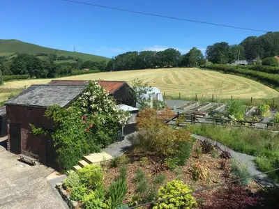 a building with a garden with a field in the background at The Royston in Llanbrynmair