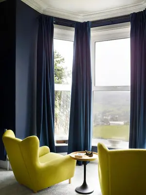 a living room with a yellow chair and a window at The Royston in Llanbrynmair