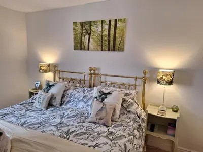 a bed in a bedroom with two lamps and a picture on the wall at 19 Upper Linney in Ludlow