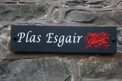 a sign on a brick wall with a red dragon on it at Plas Esgair in Llanbrynmair