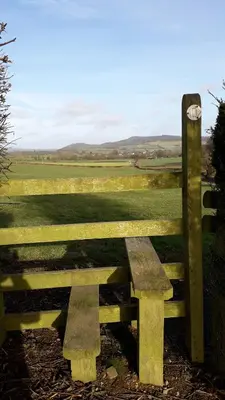 a wooden bench sitting in front of a fence at Lucea Cottage in Craven Arms
