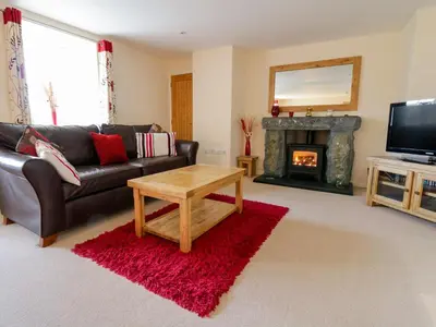 a living room with a leather couch and a fireplace at Tyn Y Buarth in Dyffryn