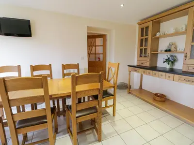 a kitchen and dining room with a wooden table and chairs at Tyn Y Buarth in Dyffryn