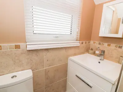 a bathroom with a sink and a toilet and a window at Edrydd in Harlech