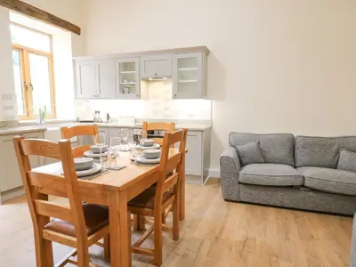 a kitchen and living room with a table and a couch at The Stables in Knighton