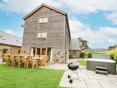 a house with a grill and a table and chairs at The Stables in Knighton