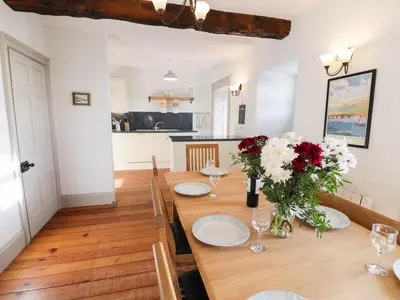 a dining room with a wooden table with flowers on it at Goronwy Cottage in Barmouth