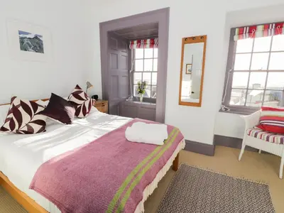 a bedroom with a large bed and a mirror at Goronwy Cottage in Barmouth