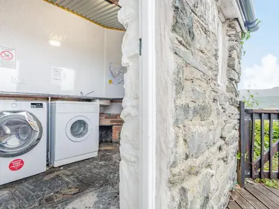 a washer and dryer next to a stone wall at Goronwy Cottage in Barmouth