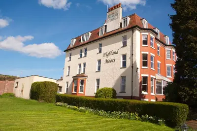 a large building on a hill with a green yard at Highland Moors in Llandrindod Wells
