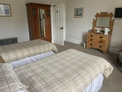 a bedroom with two beds and a dresser and a mirror at Highland Moors in Llandrindod Wells