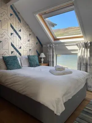 a bedroom with a large bed with a large window at Tynycornel Hotel in Tal-y-llyn
