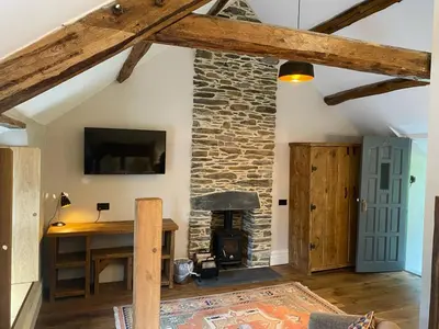 a living room with a stone fireplace and a table at Tynycornel Hotel in Tal-y-llyn